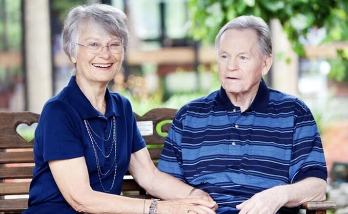 Husband and wife sitting together on a bench outdoors at Traditions of Zanesville in Zanesville, Ohio.